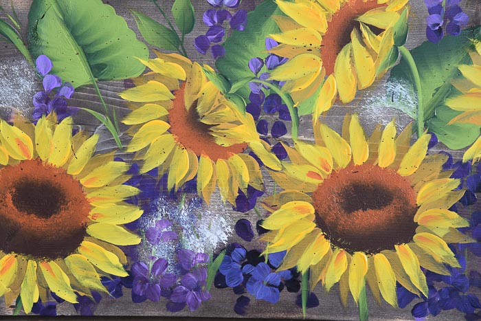 close up of sunflower and delphiniums painting on stained wood