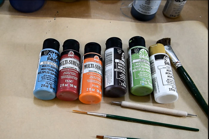 folk art paint colors with painting tools on a brown paper background