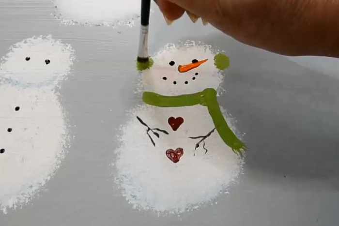 painting on snowman earmuffs with scruffy brush and green paint