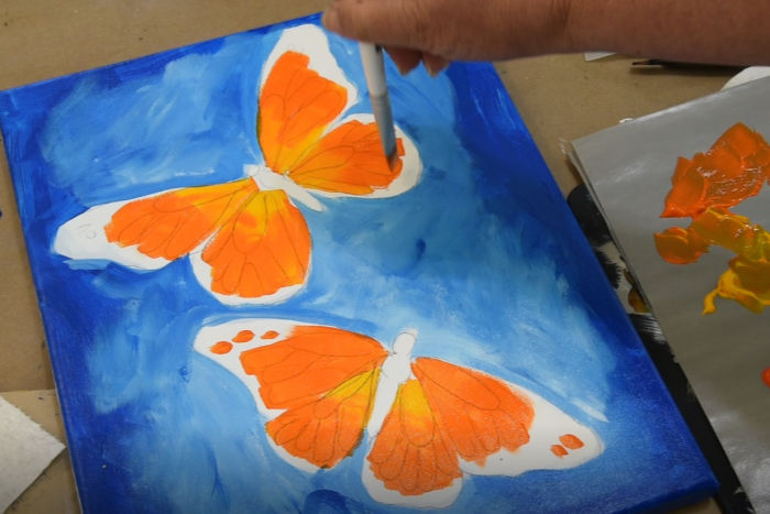 Add more orange to the paint brush then apply to butterflies wings