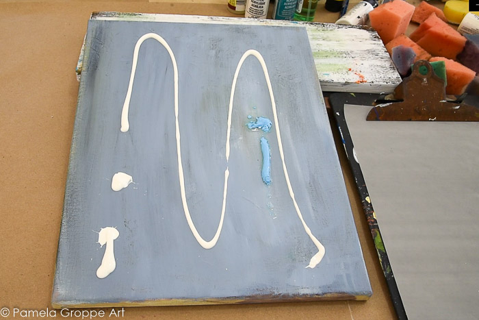 Warm white and coastal blue paint squirted on canvas