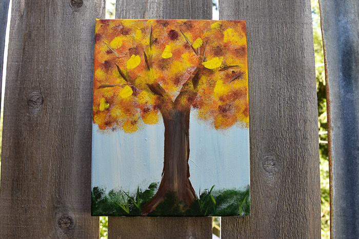 Fall tree painting hanging on fence