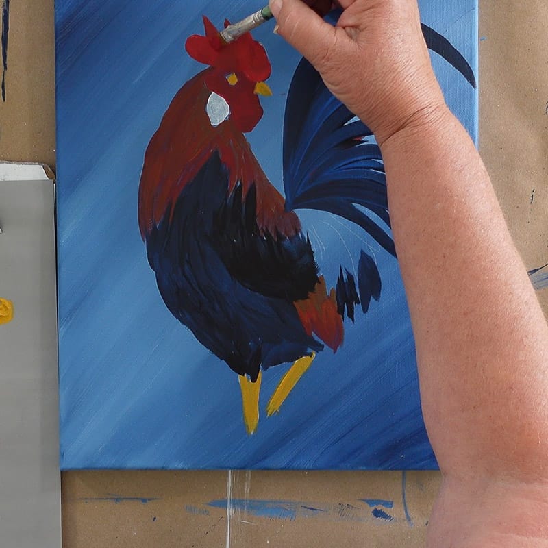 Painting another layer of cardinal red on rooster comb and wattle, pamela groppe art