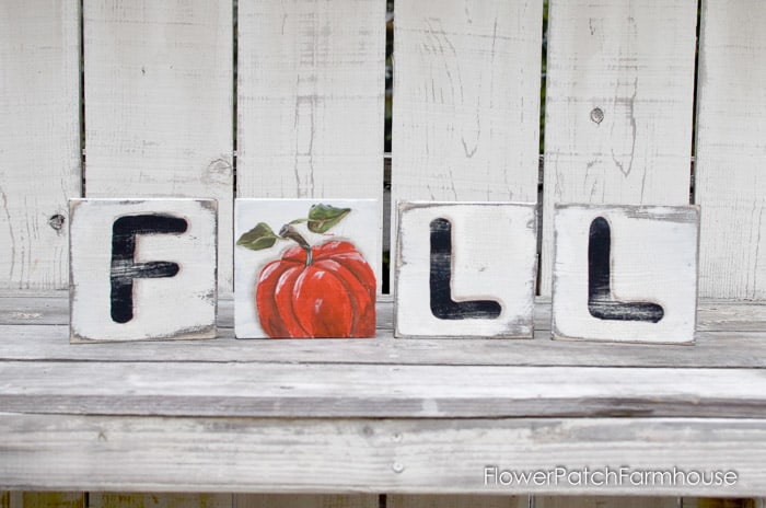 diy scrabble wood tiles painted with the letters f, then a pumpkin for A, then L, and L, lined up to spell Fall