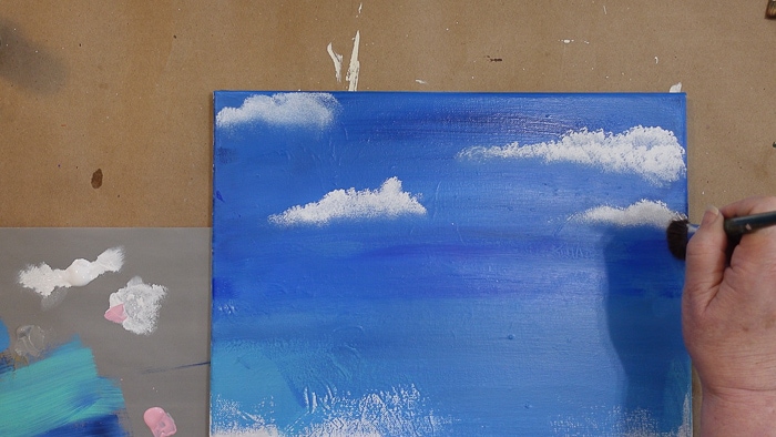 painting a cloud tapping white onto blue painted sky with scruffy brush