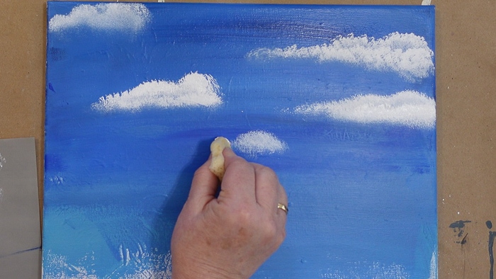 tapping white paint onto sky background to paint an easy cloud