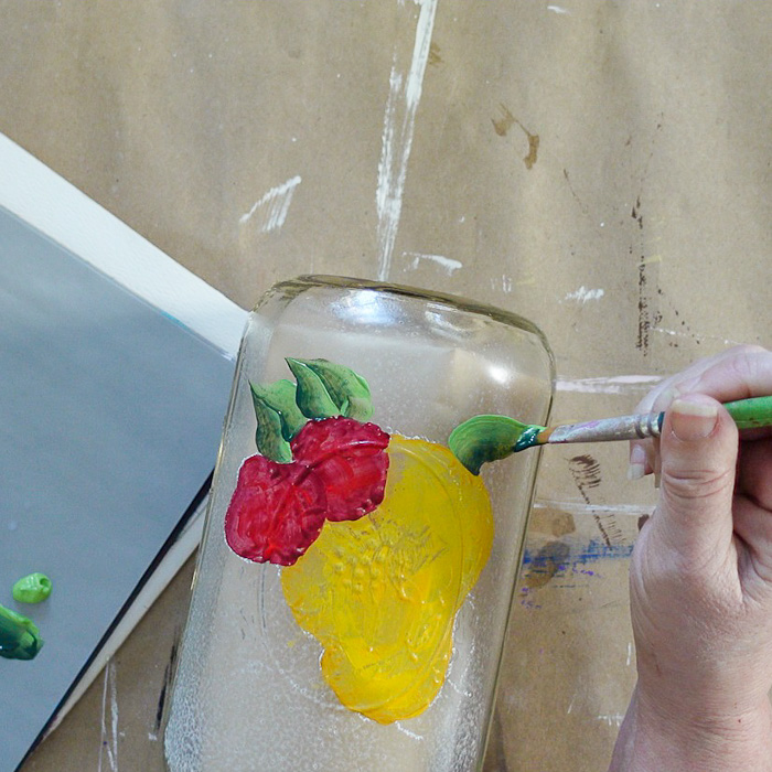 painting leaves on the glass jar by the pears and strawberries