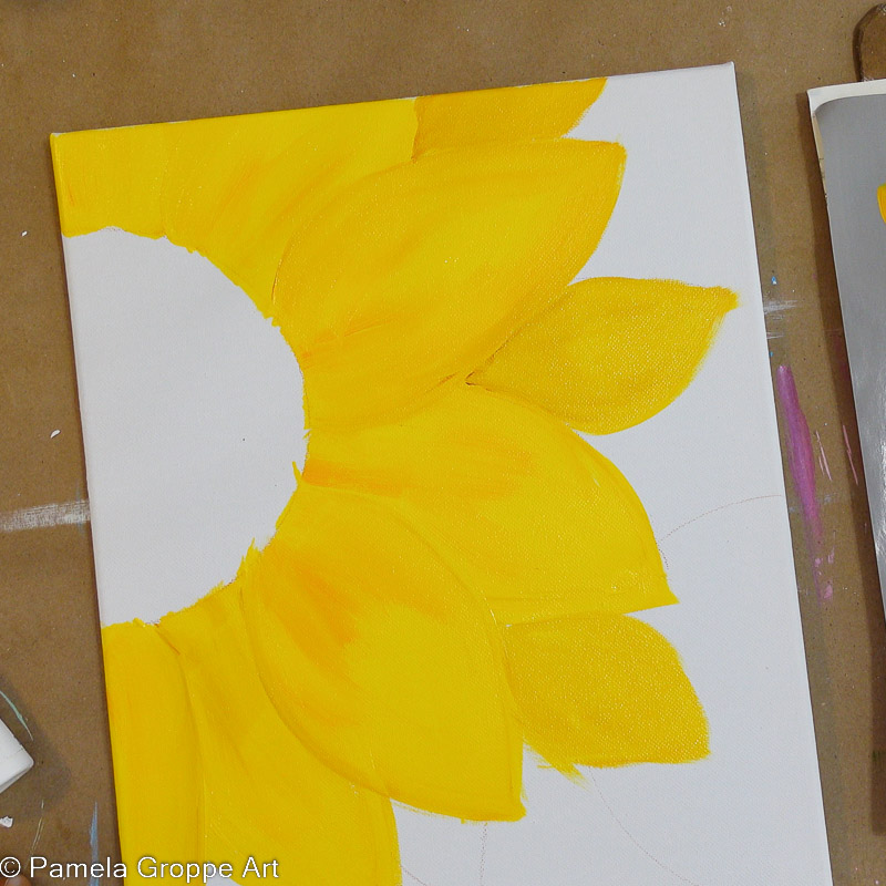 Adding second layer of sunflower petals to sunflower painting in acrylics on white canvas