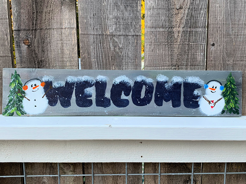 Welcome Winter porch sign with everygreens and snowmen painted in acrylics on it.