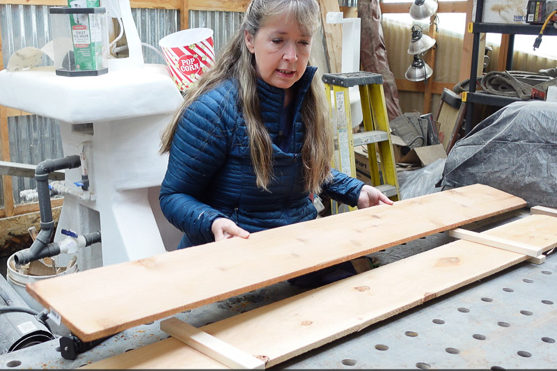 woman restacking wood boards for drying properly