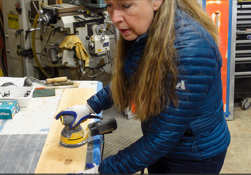 woman sanding a cedar fence board to make it smooth