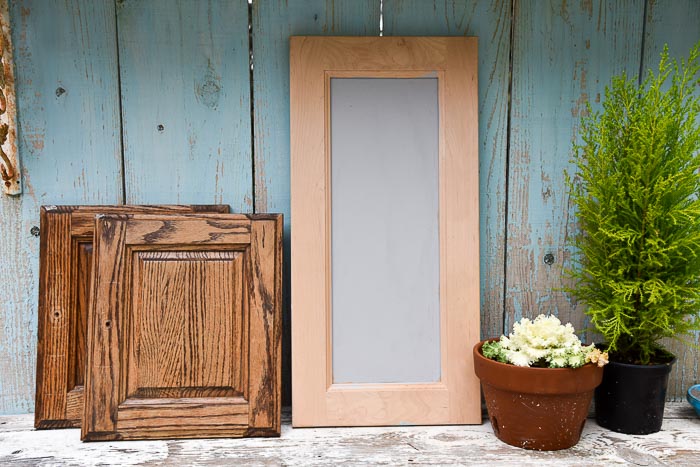 cabinet doors stacked on a table with plants beside them