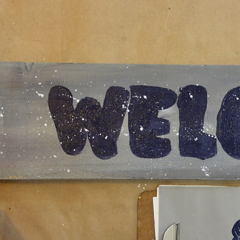 welcome sign in painting process, adding fly specking