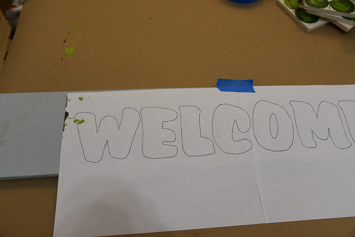 welcome sign pattern taped to gray base painted wood board