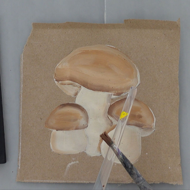 tapping one brush on another to create fly specking on the mushroom painting