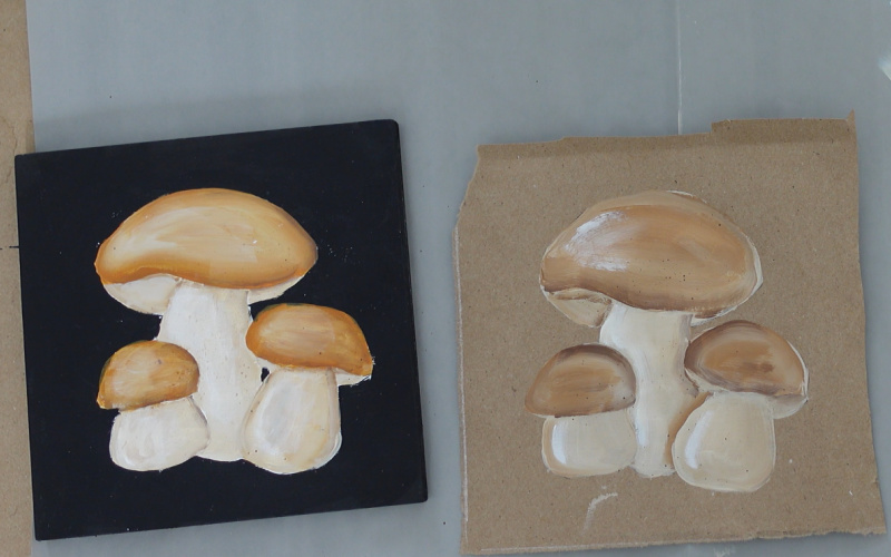 two square mushroom paintings, one done on a black background and the other on brown craft paper, both are painted in acrylics